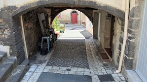 A narrow cobblestone street under a stone archway with a red door in the background. - Magnificent apartment on the outskirts of St Tropez (Cogolin)