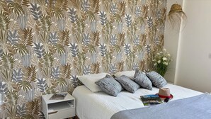 A bedroom with a patterned wallpaper, a bed with striped bedding, a nightstand, and a bedside table. - Magnificent apartment on the outskirts of St Tropez (Cogolin)