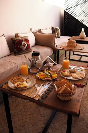 A breakfast setup on a wooden table with a variety of foods, a coffee maker, and a glass of orange juice. - Stylish Double -Twin & Breakfast in Prime Location (Marrakech)