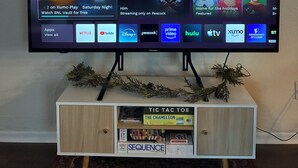 A television on a stand with a Christmas tree decoration above it.