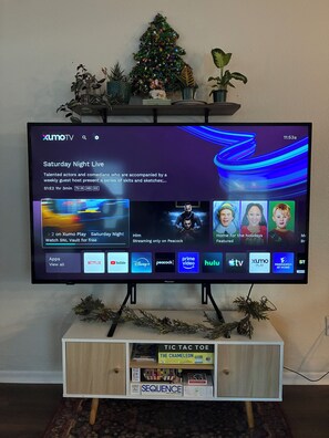 A television on a stand with a Christmas tree decoration above it.
