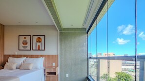 A modern hotel room with a large bed, a nightstand, a wall-mounted light, and two framed artworks. - Comfortable Studio in Caminho das Árvores (Salvador)