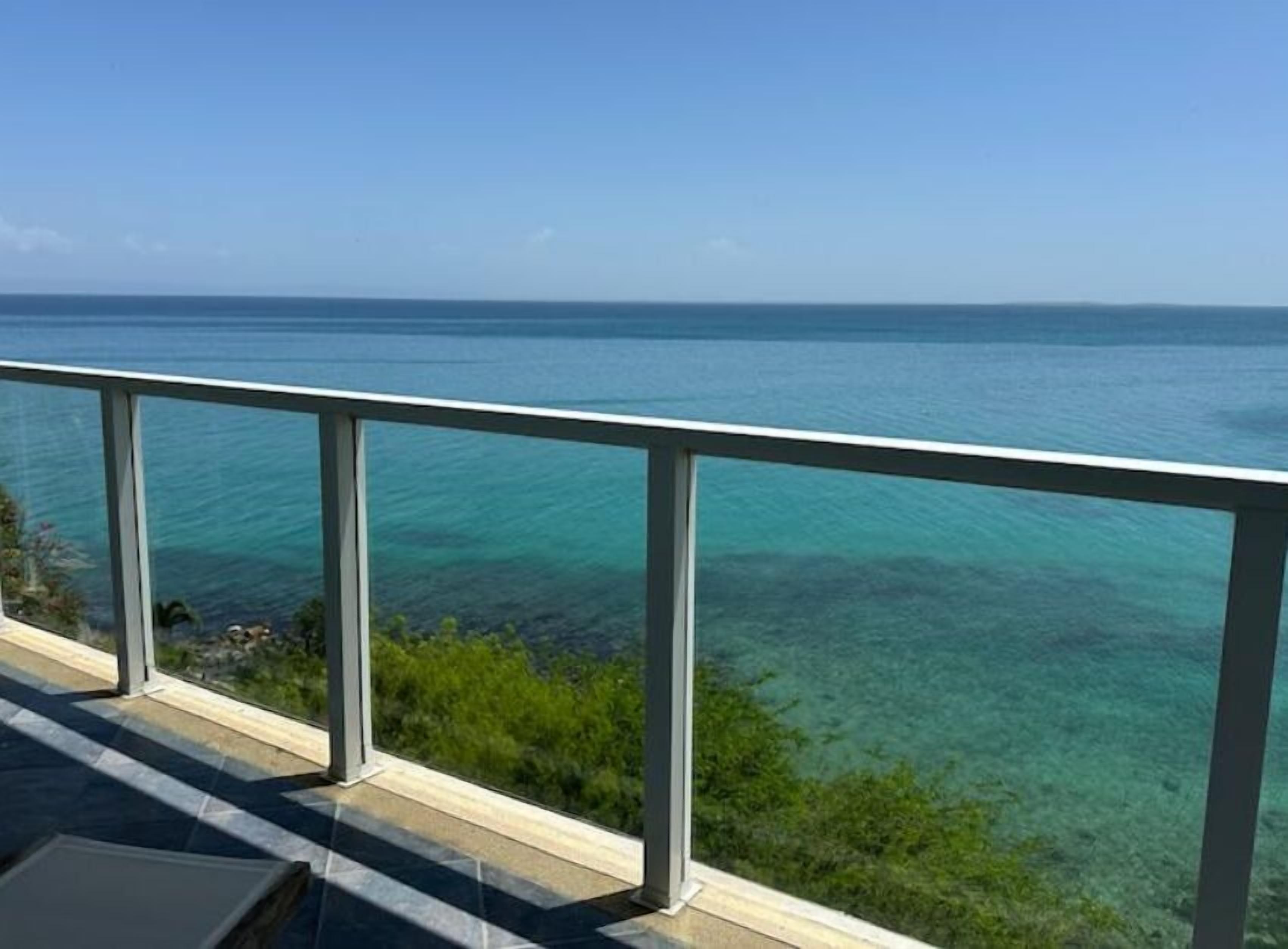 Een balkon met een helder uitzicht op de oceaan en een verre kustlijn.