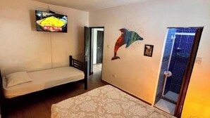 A room with a bed, a sofa, a television mounted on the wall, and a dolphin mural. - Amazing private room for 3 to 200 meters from Tayrona Park (Santa Marta)
