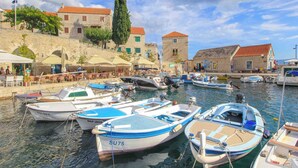 A marina with boats docked, stone buildings, and outdoor seating areas. - Stone House With two Balconies and the sea View (Bol)