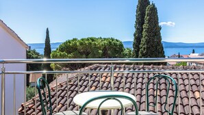 A balcony with two round tables and chairs, overlooking a tiled roof and a body of water. - Stone House With two Balconies and the sea View (Bol)
