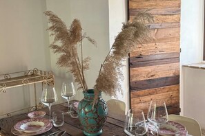 Ein Esstisch mit einer dekorativen Vase und Pampasgras, umgeben von leeren Weingläsern und Tellern.