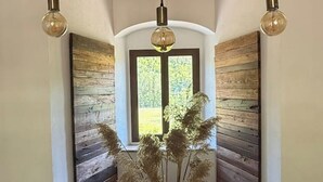 Una camera d'angolo con pareti in legno a pannelli, una finestra vista su spazi verdi e un vaso con piante essiccate.