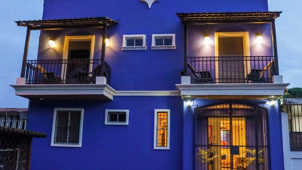Un immeuble de deux étages, à la façade bleue, doté de balcons et d’une entrée fermée par un portail.