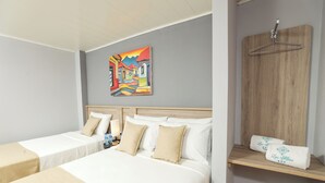 Une chambre d’hôtel avec deux lits, une tête de lit en bois, un tableau au mur et une étagère en bois avec des serviettes.