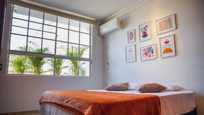 A bedroom with a bed, a window, and wall art.