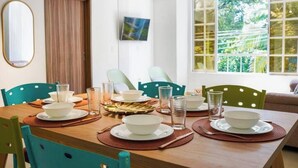 A dining area with a wooden table set for four, surrounded by turquoise chairs.