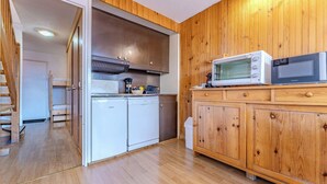 Una cocina compacta con armarios de madera, un microondas y un lavavajillas.