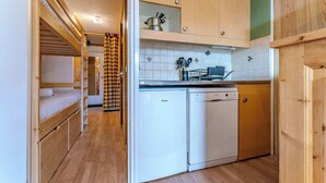 Una cocina compacta con armarios de madera, lavavajillas y pileta.