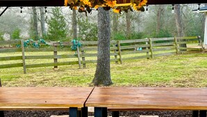 An outdoor wooden picnic table with benches, surrounded by a red and white striped mat, under a canopy with a sunflower light fixture. - Beautiful country home escape for a Country Christmas in Bellville, TX (Bellville)