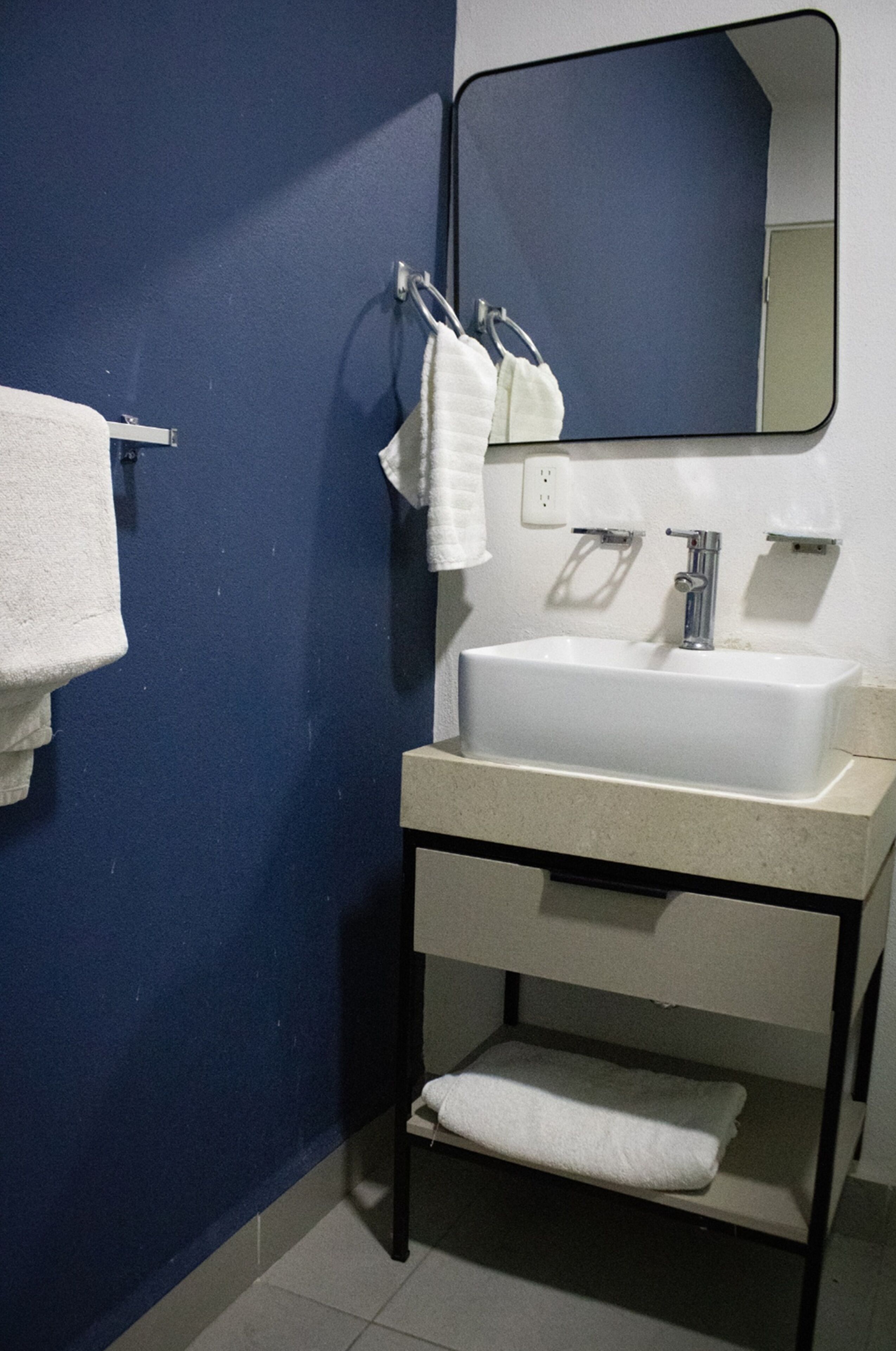 A bathroom with a white sink, a mirror, and a towel rack.