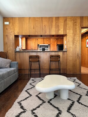 A modern kitchen with wooden cabinetry, a microwave, and two bar stools. - Dodger Stadium House for Rent! 5bedroom 3 Bath, with private patio! (Los Angeles)