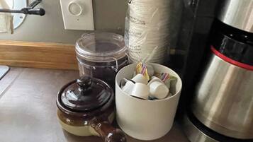 Un comptoir de cuisine avec une machine à café, une théière et un récipient contenant des sachets de thé.
