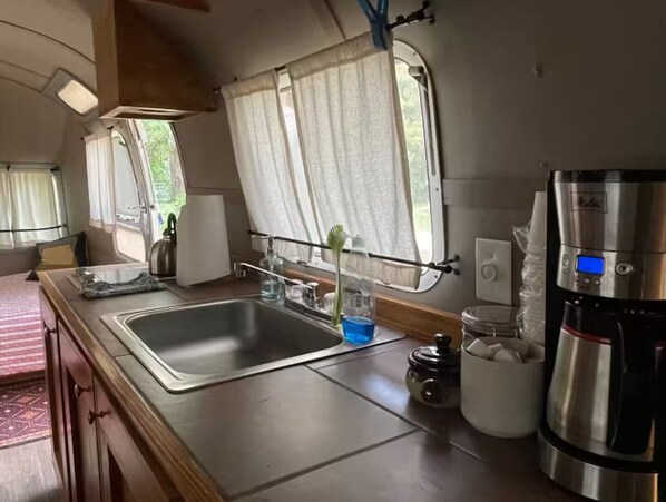 A compact kitchen with a sink, a coffee maker, and a window with curtains. - Country setting in South ATX! (Austin)