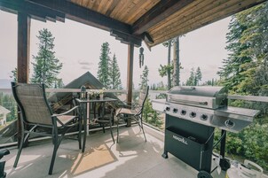 Un patio al aire libre con una parrilla, sillas y una mesa.