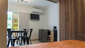Une chambre à coucher comprenant un lit, un bureau avec une chaise, une télévision et une armoire.