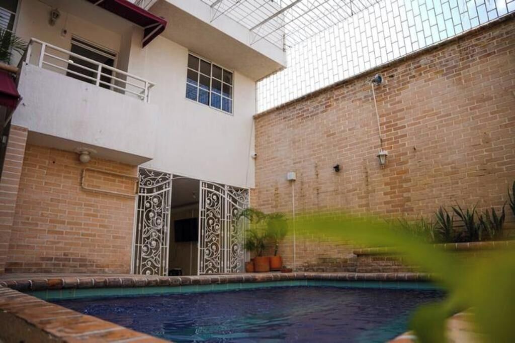 A courtyard with a swimming pool, a brick wall, and a white building with a balcony.