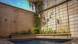 Une piscine entourée de murs en briques et agrémentée de plantes en pot.