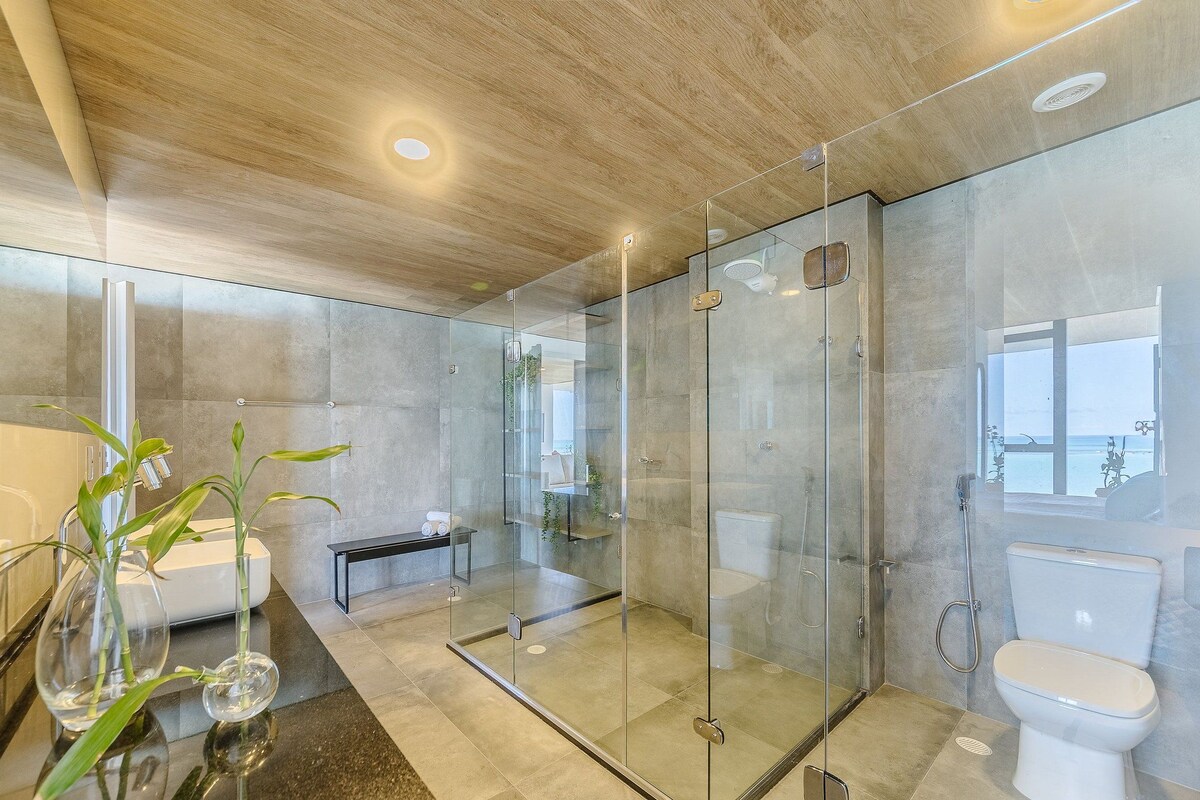 A modern bathroom with a glass-enclosed shower, a bathtub, and a toilet.