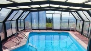 Una piscina con cerramiento de vidrio, rodeada por un patio de ladrillo.