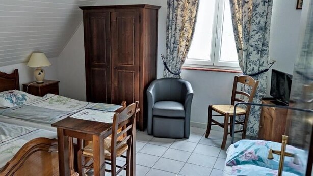 Un dormitorio con cama, escritorio, silla, armario, lámpara y ventana con cortinas.