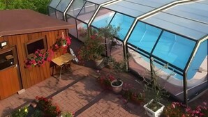 Un invernadero con techo transparente, rodeado de plantas y flores en macetas.