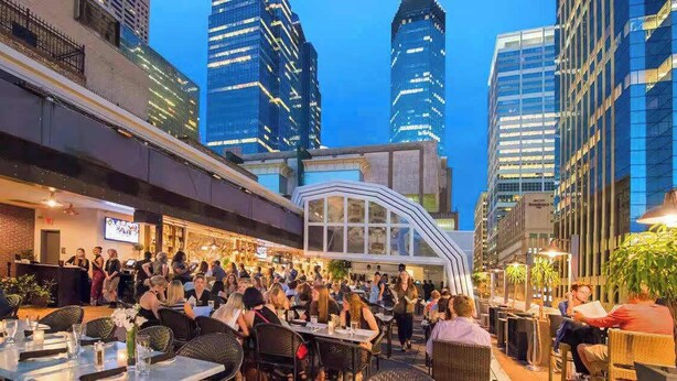 An outdoor dining area with tables and chairs, surrounded by high-rise buildings. - Coze Studio Unit Near Downtown MN and Airport (Minneapolis)