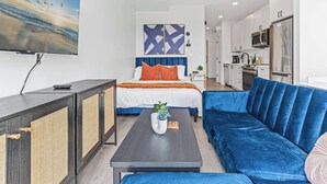 A modern hotel room with a bed, a sofa, a coffee table, and a TV. - Coze Studio Unit Near Downtown MN and Airport (Minneapolis)