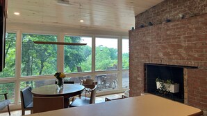 A dining area with a brick fireplace, large windows, and a round table with chairs. - Centrally Located Bright Family Home with Peaceful Natural Views and Central A/C (Burlington)