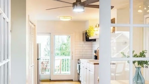 Une cuisine moderne avec des armoires blanches, un plan de travail en bois et un ventilateur de plafond.