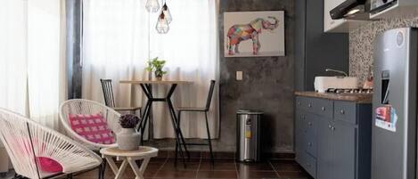 Cozinha compacta com área de refeições, com mesa e cadeiras, geladeira e lixeira.