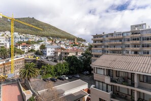 A residential area with multi-story buildings, a construction crane, and a hilly backdrop. - Stylish Green Point Apartment | Rooftop Pool (Cape Town)