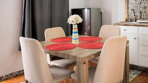 A dining area with a wooden table, four chairs, and a vase with flowers. - Modern, upscale loft one block from the walkway (San Cristobal d elas Casas, Chiapas)
