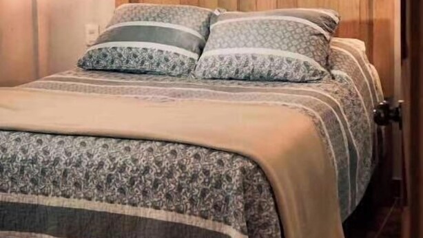 A bedroom with a wooden headboard, a bed with patterned bedding, and a hanging light fixture. - Modern, upscale loft one block from the walkway (San Cristobal d elas Casas, Chiapas)