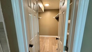 A hallway with white doors, beige walls, and a wooden floor. - 1BR Hideaway • Calm & Private (Beaumont)