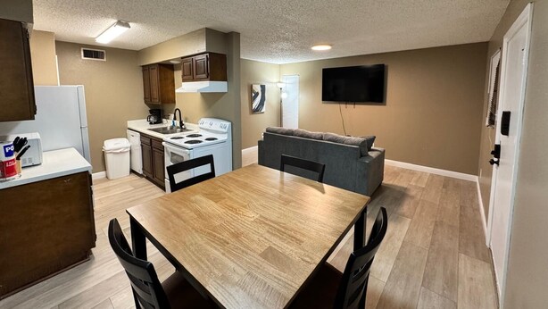A compact kitchen with a dining table and chairs, a built-in oven, and a microwave. - 1BR Hideaway • Calm & Private (Beaumont)