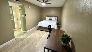 A bedroom with a bed, a ceiling fan, and a dining table with a plant. - 1BR Hideaway • Calm & Private (Beaumont)