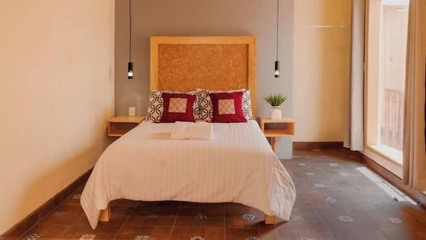 A bedroom with a large bed, two bedside tables, a headboard, and a window.
