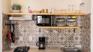 Eine kleine Küche mit Gasherd, Mikrowelle, Kaffeemaschine und Spüle.