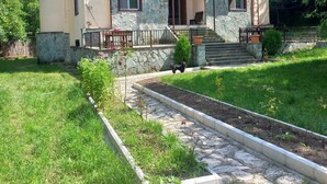 A two-story house with a stone facade, a balcony, and a garden area with a pathway. - Noor Dilijan (Dilijan)