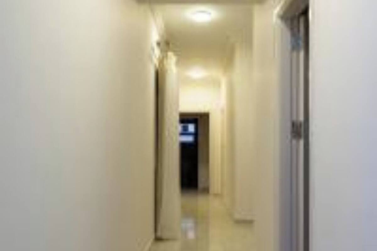 A narrow, well-lit hallway with a shiny floor, leading to a door at the end.