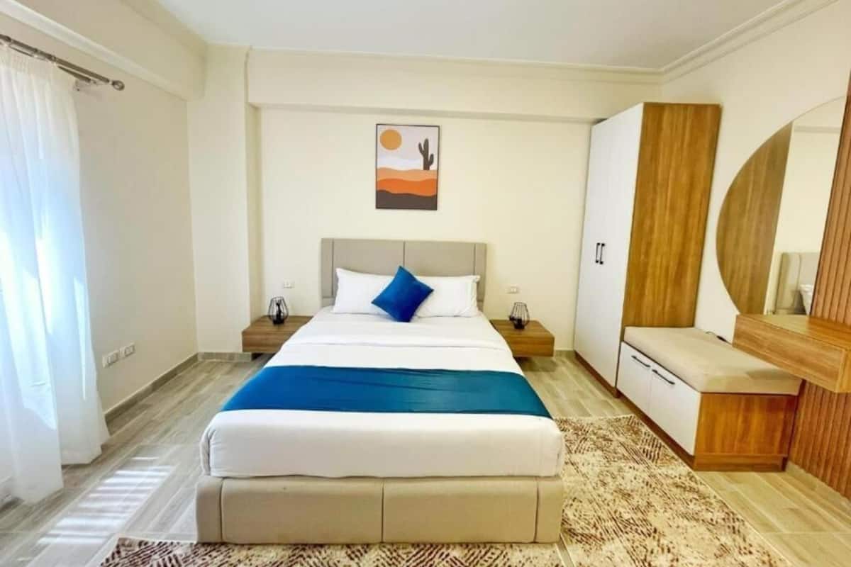 A bedroom with a bed, nightstands, a dresser, and a mirror.