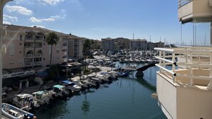 A marina with boats docked, a restaurant named 'Salombo' on the left, and a building with balconies on the right.