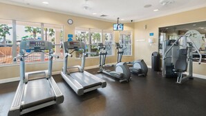 Une salle de sport équipée de tapis de course, de vélos elliptiques et de matériel de musculation.