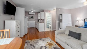 A compact living space with a dining area, a sofa, a TV, and a kitchenette. - Riverview (Saugatuck)